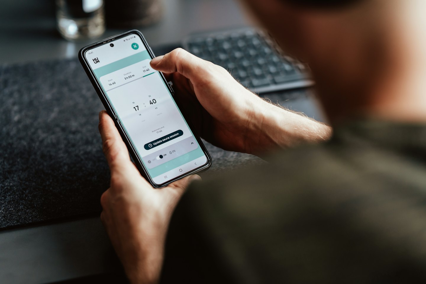 Hands using a smartphone app to book a sauna session.